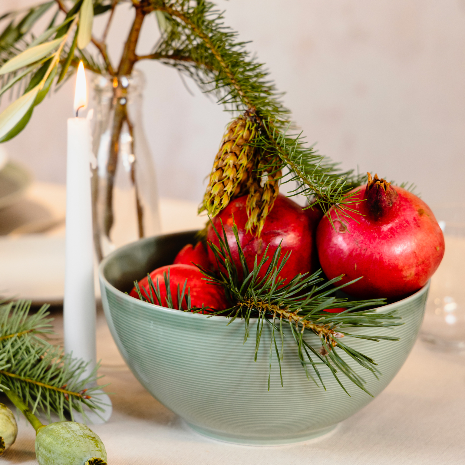 Several pomegranates in a green Thomas Loft Moss Green bowl and fir branches as decoration
